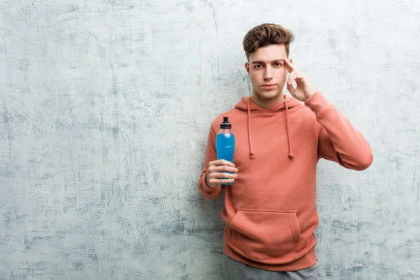 Pemuda Olahraga Memegang Minuman Energi Menunjuk Kuilnya Dengan Jari Berpikir — Stok Foto