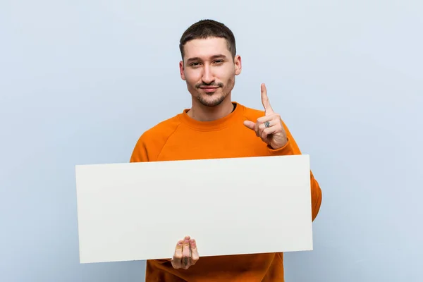 Jovem Caucasiano Segurando Cartaz Mostrando Número Com Dedo — Fotografia de Stock