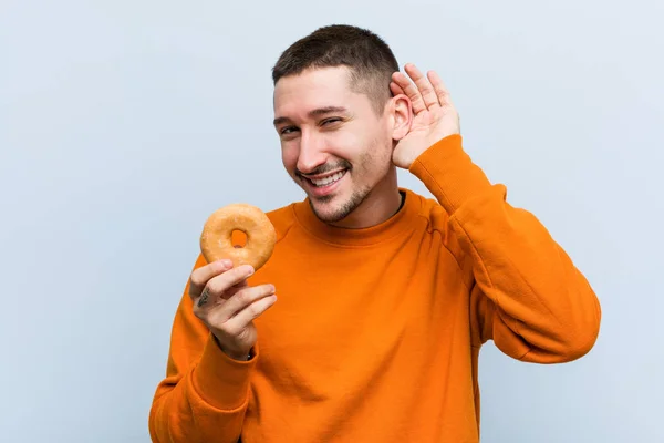 Joven Caucásico Sosteniendo Donut Tratando Escuchar Chisme — Foto de Stock