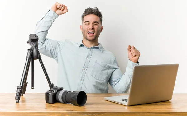 Young handsome photography teacher celebrating a special day, jumps and raise arms with energy.