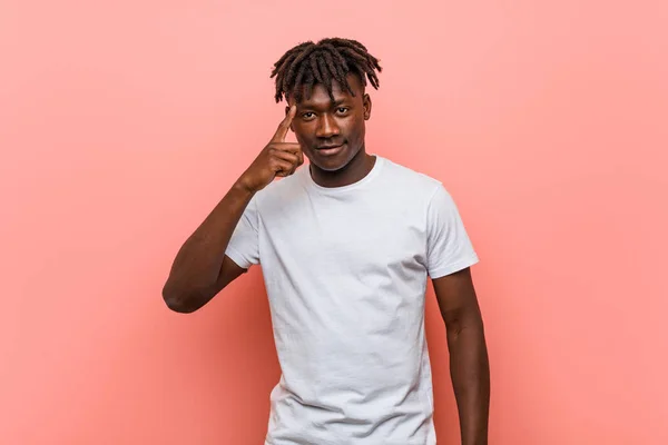 Young african black man pointing temple with finger, thinking, focused on a task.