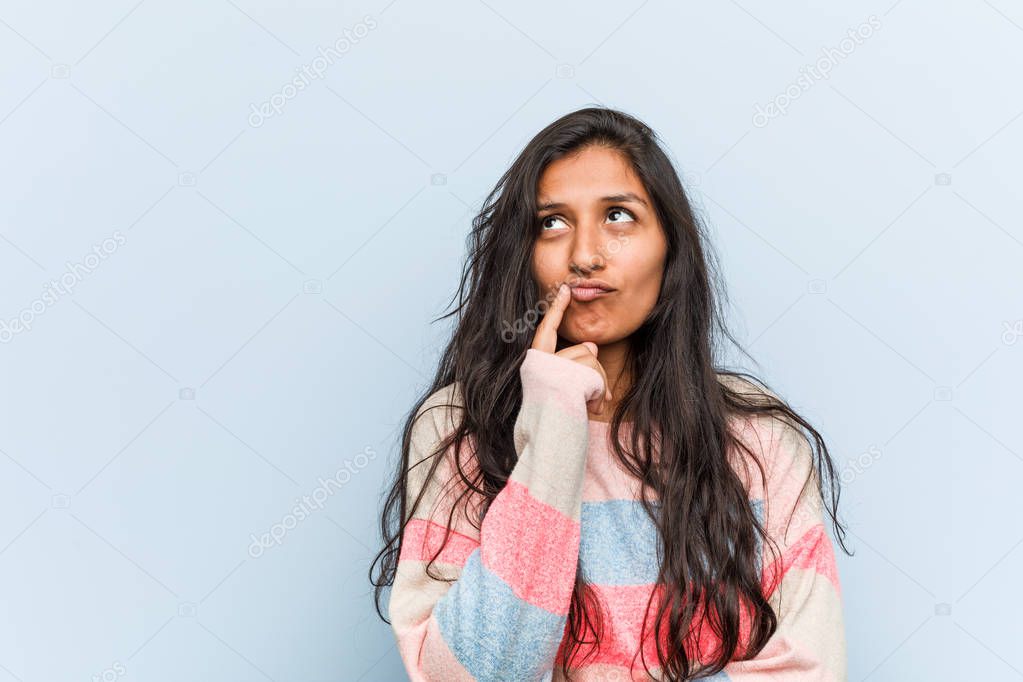 Young fashion indian woman looking sideways with doubtful and skeptical expression.