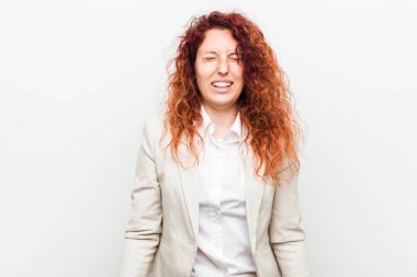 Genç doğal kızıl saçlı iş kadını beyaz arka plan karşı izole güler ve gözleri kapatır, rahat ve mutlu hissediyor.