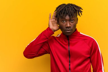 Genç Fitness Afrikalı adam bir dedikoduyu dinlemeye çalışıyor.