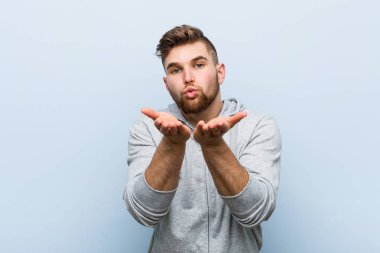 Genç yakışıklı fitness adam dudakları katlanır ve hava öpücük göndermek için avuç içi tutarak.