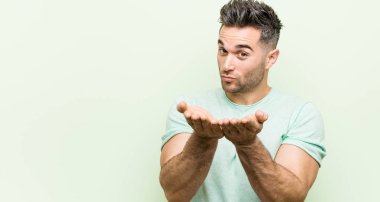 Yeşil bir arka planda katlanır dudaklara karşı genç yakışıklı adam ve hava öpücük göndermek için avuç tutan.