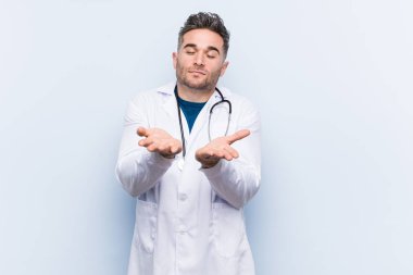Kamera sunan, avuç içi ile bir şey tutan genç yakışıklı Doktor adam.