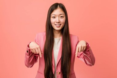 Genç iş Çinli kadın parmaklı pembe takım elbise puan aşağı parmaklar, pozitif duygu.