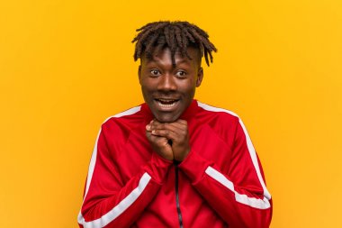 Genç Fitness siyah adam çene altında eller tutar, mutlu bir kenara bakıyor.