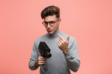 Genç entelektüel adam bir film kamera tutan bir parmak ile size işaret sanki davet civarla.