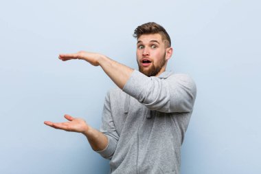 Genç yakışıklı fitness adam şok ve elleri arasında bir kopya alanı tutarak şaşırdım.