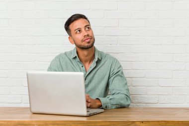 Genç Filipino adam oturan onun laptop ile çalışma hedefleri ve amaçları elde hayal