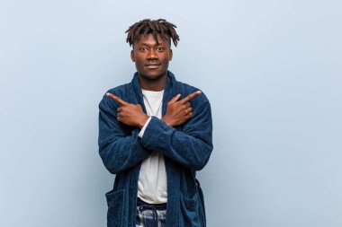 Pijama noktaları yan giyen genç Afrikalı siyah adam, iki seçenek arasında seçim yapmaya çalışıyor.