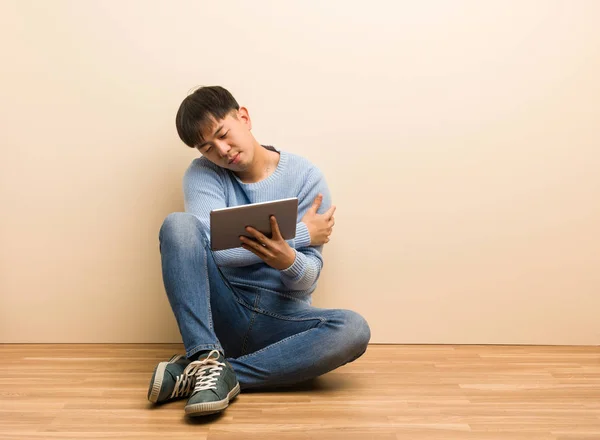 Young Chinese Man Sitting Using His Tablet Giving Hug — Stock Photo, Image