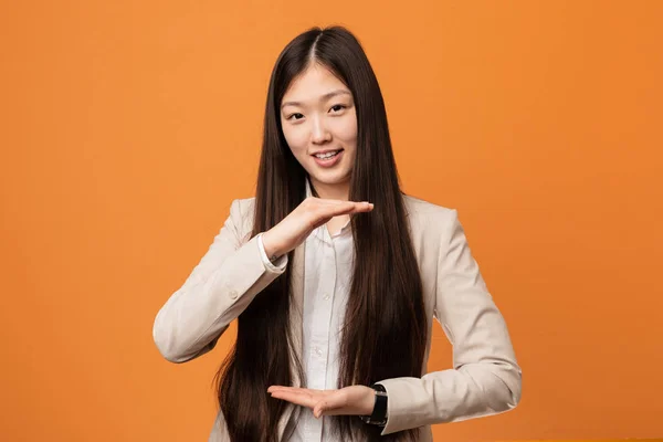 Young business chinese woman holding something with both hands, product presentation.
