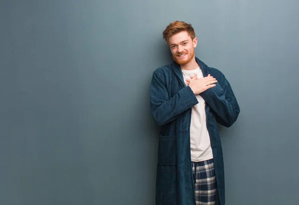 Young redhead man in pajama doing a romantic gesture