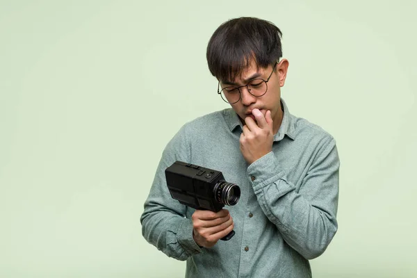 Joven Chino Sosteniendo Una Cámara Vintage Relajado Pensando Algo Mirando — Foto de Stock