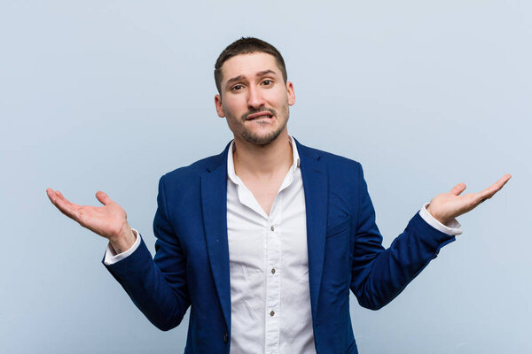 Молодой кавказский бизнесмен смущен и сомнительно поднимает руки, чтобы держать пространство для копирования.
.