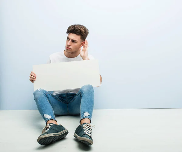 Jovem Segurando Cartaz Sentado Seu Chão Casa Tentando Ouvir Uma — Fotografia de Stock