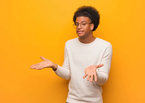 Jovem Afro Americano Sobre Uma Parede Laranja Confusa Duvidosa — Fotografia de Stock