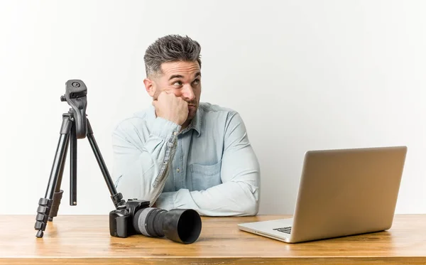 Young handsome photography teacher who feels sad and pensive, looking at copy space.