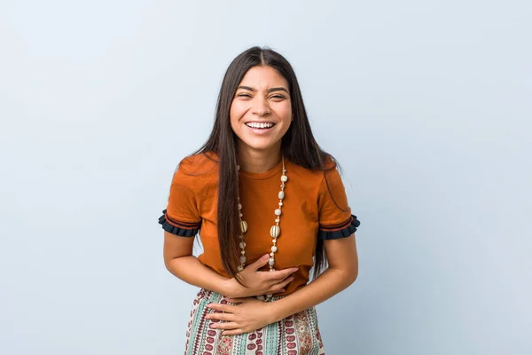 Young arab woman laughs happily and has fun keeping hands on stomach.