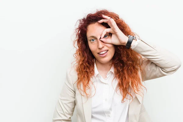 Young natural redhead business woman isolated against white background excited keeping ok gesture on eye.