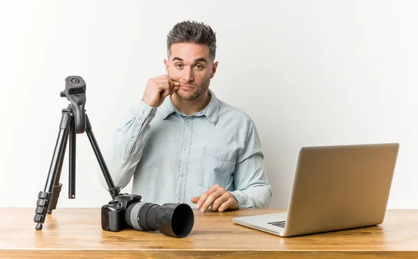 Young handsome photography teacher with fingers on lips keeping a secret.