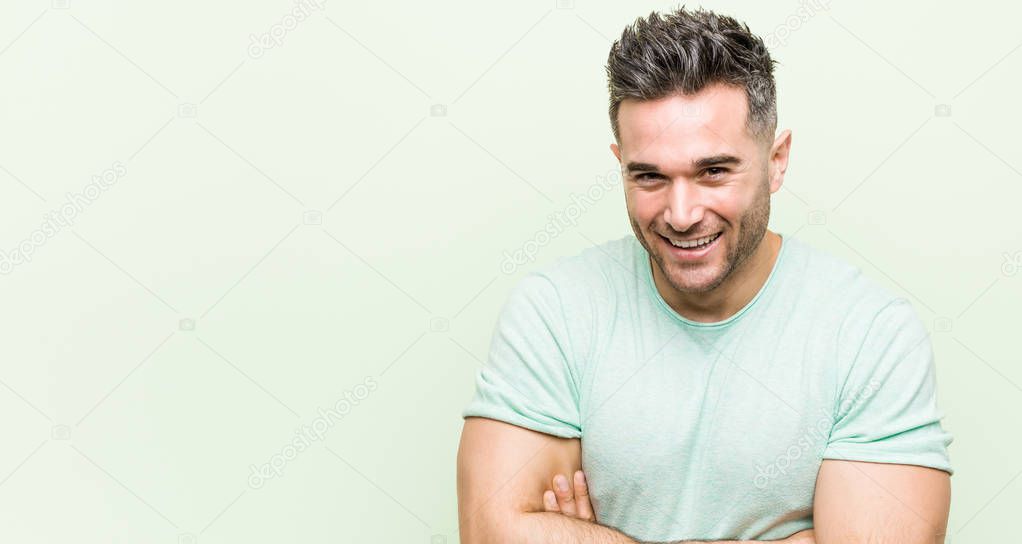 Young handsome man against a green background laughing and having fun.