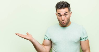 Yeşil bir arka plana karşı genç yakışıklı adam palmiye üzerinde kopya alanı tutan etkilendim.