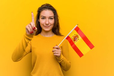Genç Avrupalı kadın tutan bir İspanyol bayrağı gösteren bir numara ile parmak.