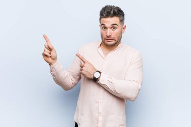 Genç yakışıklı serin adam bir kopya alanı için işaret parmakları ile şok.