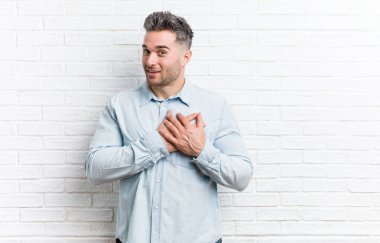 Bir tuğla duvara karşı genç yakışıklı adam dostça bir ifade vardır, göğüs eve avuç basarak. Aşk kavramı.