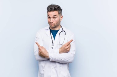 Genç yakışıklı doktor adam yan noktalar, iki seçenek arasında seçim yapmaya çalışıyor.