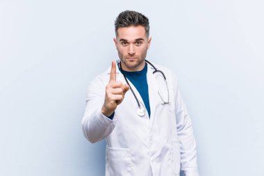 Genç yakışıklı doktor adam parmak ile bir numara gösteren.