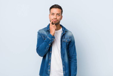 Genç yakışıklı filipinli adam şüpheli ve şüpheci ifade ile yan bakıyor.
