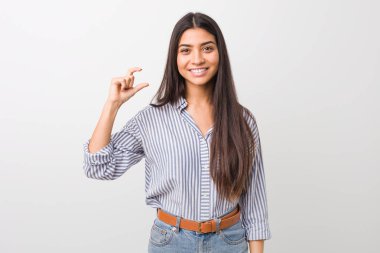 Young pretty arab woman holding something little with forefingers, smiling and confident. clipart