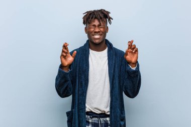 Genç afrikalı siyah adam şans için parmakları geçiş pijama giyiyor