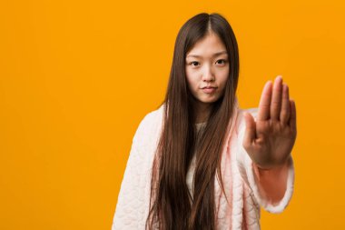 Pijama genç Çinli kadın uzanmış el ile dur işareti gösteren ayakta, sizi engelleyen.