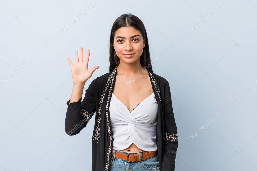 Young natural and pretty arab woman smiling cheerful showing number five with fingers.
