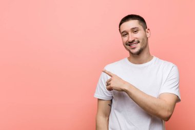 Genç rahat adam gülümseyerek ve bir kenara işaret, boş alanda bir şey gösteren.
