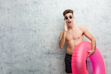 Pembe şişme çörek tutan genç adam ön heyecanlı bağırıyor bir mayo giyiyor.