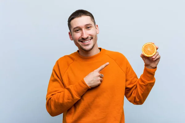Νέος Καυκάσιος Άνθρωπος Που Κρατά Ένα Πορτοκαλί Χαμόγελο Που Δείχνει — Φωτογραφία Αρχείου