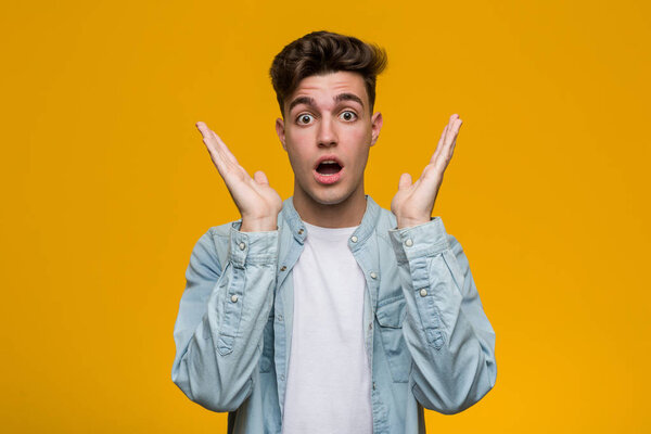 Молодой красивый студент в джинсовой рубашке удивлен и шокирован
.