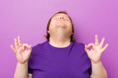 Genç otantik kızıl saçlı şişman adam zor iş gününden sonra rahatlatır, o yoga yapıyor.