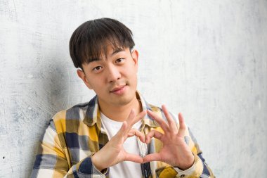 Genç Çinli adam elleri ile bir kalp şekli yapıyor closeup yüz