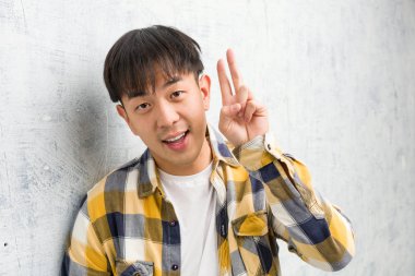 Genç Çinli adam yakın çekim eğlenceli ve mutlu zafer bir jest yapıyor yüz