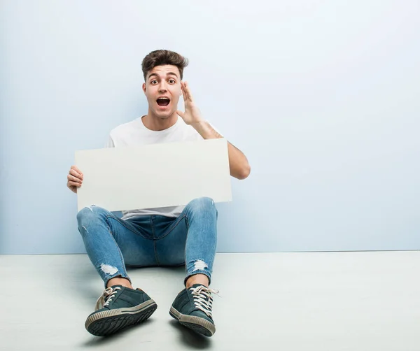 Young Man Holding Placard Sitting His Home Floor Shouting Excited — Stock Photo, Image