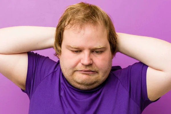 Young authentic redhead fat man covering ears with hands trying not to hear too loud sound.