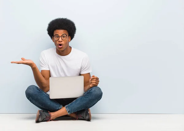 Jonge Zwarte Man Zittend Vloer Met Een Laptop Holding Iets — Stockfoto